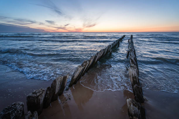 Old fishing boat pier wooden poles near Koshrags. Baltic sea can be seen in the background