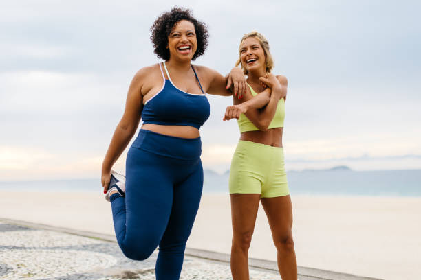 istock Two happy women doing warm-up exercises on the beach 1592133603