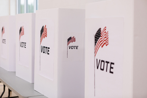 A row of voting booths printed with the American flag stand ready for voters.