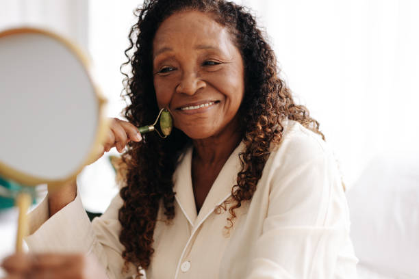 istock Anti-aging skincare routine: Mature woman using a jade roller on her face 1592133768