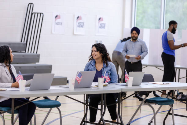 istock While people vote at booths behind them, volunteers chat together 1592138178