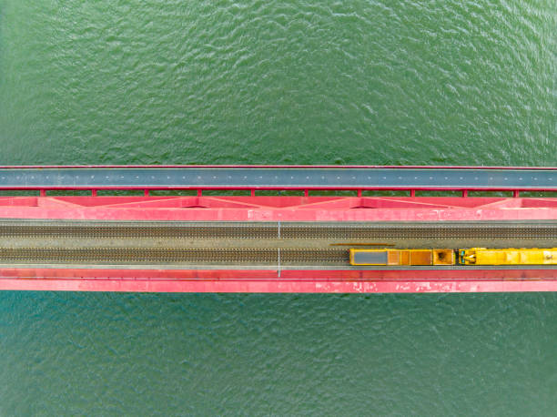 istock Railroad tracks on a railway bridge over a river with a train passing seen from above 1592140354