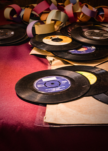 A pile of old fashioned 45 single vinyl records and coloured paper chain.