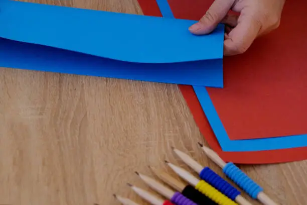 Photo of closeup woman holding one blue colored sheet of paper in her hands, material for scrapbooking, origami, folds figures from paper, concept of needlework, artisans crafting and creating by hand