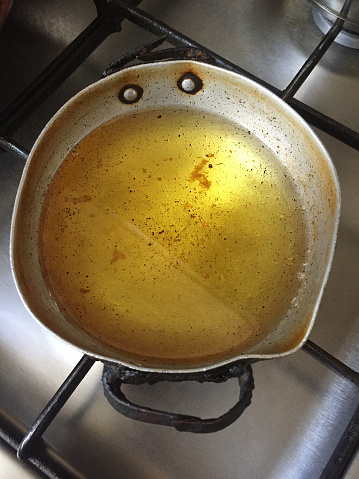 Waste cooking oil in a cooking pan on burner stove top