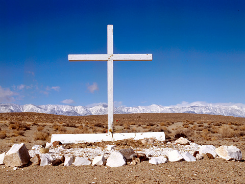 Old abandoned nameless grave in the desert with snowed mountains at the background