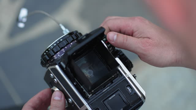 The photographer's hand sets the mechanical settings in the camera