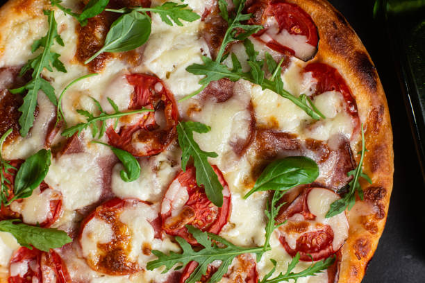 istock Pizza with ham,tomatoes and mozzarella on a dark background 1592184383