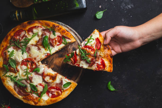 istock Pizza with ham,tomatoes and mozzarella on a dark background 1592184390