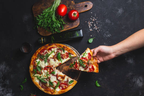 istock Pizza with ham,tomatoes and mozzarella on a dark background 1592184917