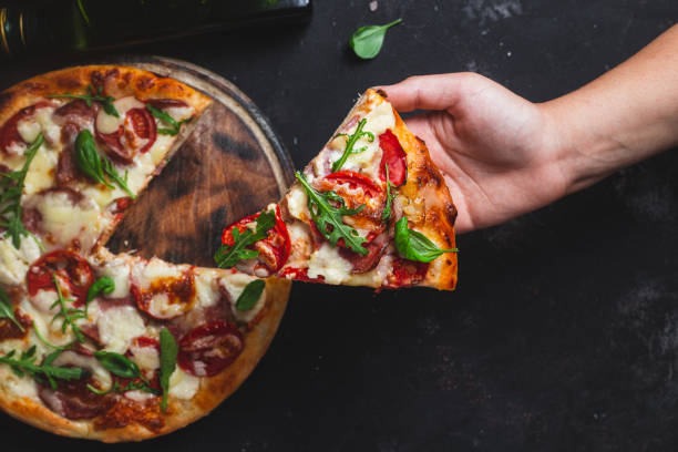 istock Pizza with ham,tomatoes and mozzarella on a dark background 1592184944