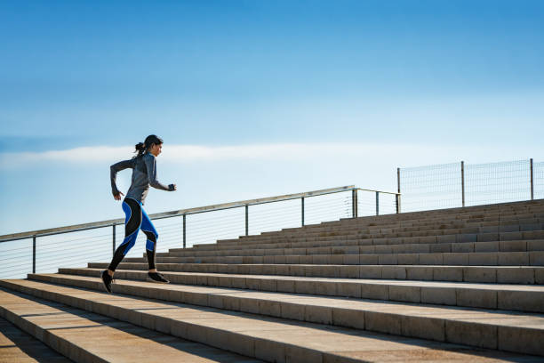istock Young sporty looking woman running on steps 1592184954