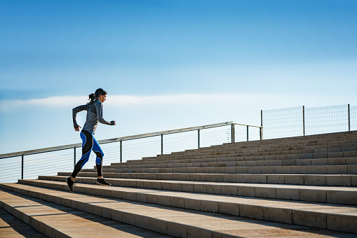 Young sporty looking woman running on steps.