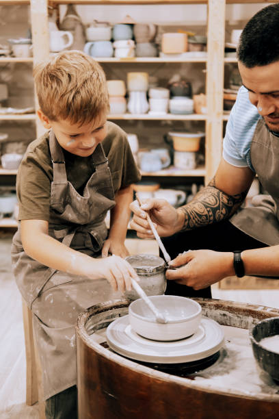 istock Pottering with son. Confident young man and little boy making ceramic pot on the pottery class 1592193567