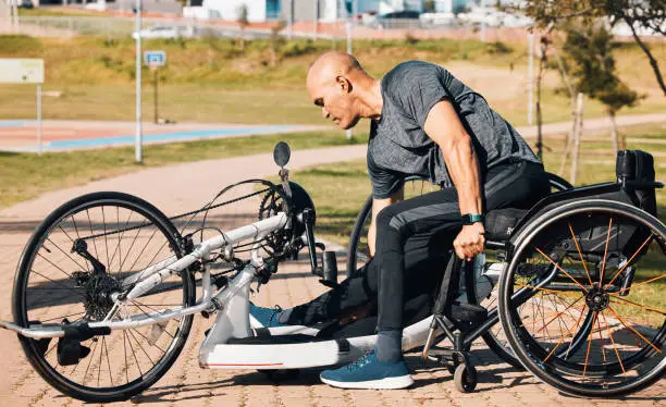Wheelchair, athlete or a man with a disability and bike for handicap race, fitness and recumbent challenge. Exercise, park and a handbike of paraplegic sports person outdoor for cardio and training