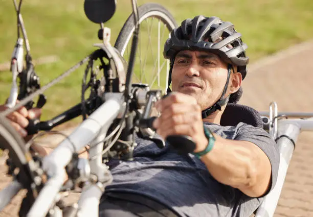 Man with disability, handbike and cycling outdoor for sports, race and endurance contest. Bicycle, male rider and athlete with physical health condition on bike with focus, competition and challenge