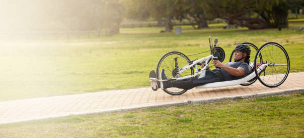 Cycling, disability and exercise with man and bike with handicap for training, sports and challenge. Fitness, workout and wheelchair with disabled person in park for cardio, wellness and health ciclismo, fitness y espacio con el hombre y el handcycle en la naturaleza para entrenamiento, concurso deportivo y desafío. ejercicio, entrenamiento y pancarta con una persona con discapacidad en el parque para maquetas de cardio y salud