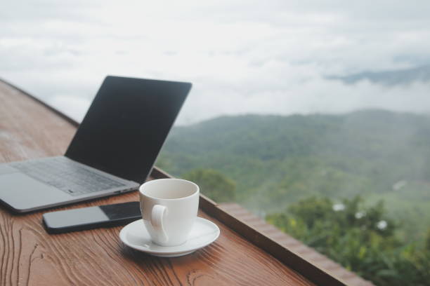 istock Young man freelancer traveler wearing hat anywhere working online using laptop and enjoying mountains view 1592211015