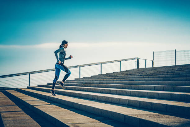 istock Young sporty looking woman running on steps 1592223424