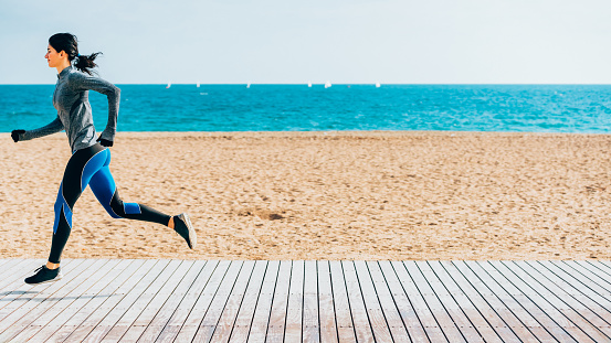 Young sporty looking woman running on beach.