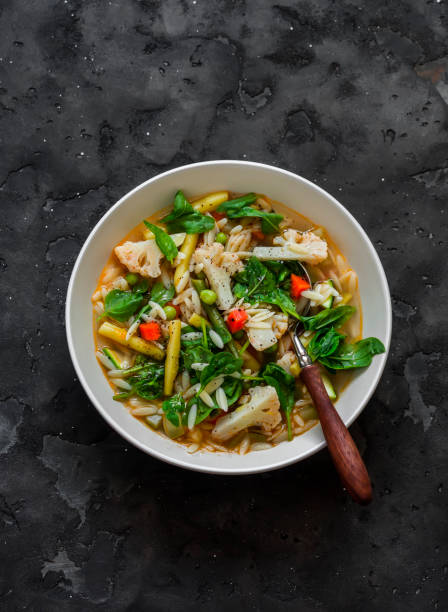 istock Vegetables and orzo pasta vegetarian minestrone soup on a dark background, top view 1592228748