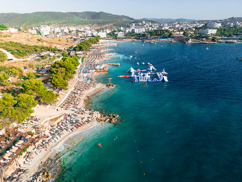 Aerial view of a crowded sand beach with umbrellas and lots of people at sunset. Albania, Dhermi and Ksamil. The islets of Ksamil, consist of four rocky islets located in direct proximity to the Ionian Sea in southern Albania.
