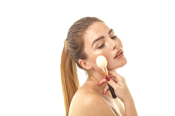 beauty portrait of real natural woman with freckles on her face and shoulders. girl holding makeup brush. white studio background. skin care concept. - real people indoors studio shot head and shoulders imagens e fotografias de stock