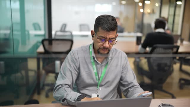 Mature man using laptop and mobile phone in the office
