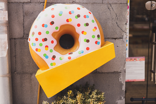 Giant donut sign in front of cafe or restaurant with empty copy space for text or advertising. Fast food and sweet junk food meal