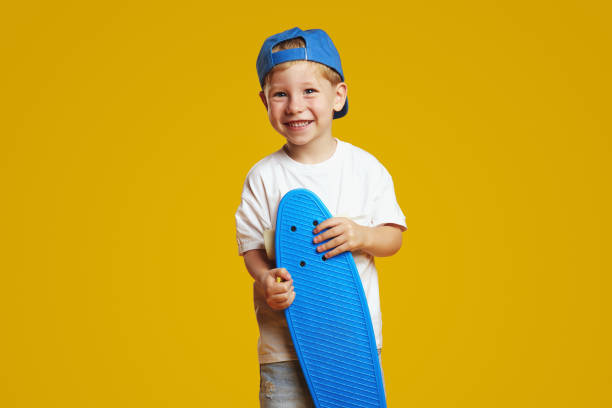 istock Happy cute kid wearing white t-shirt and blue cap while holding longboard and smiling 1592266021