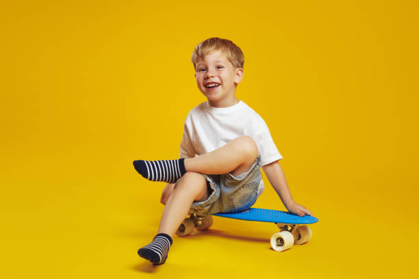 istock Happy child boy in white tshirt smiling and looking at camera while sitting on modern skateboard 1592267590