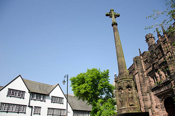 Cross outside Chester Cathedral in the old Roman city of Chester. On the left are some of the old Victorian buildings on St Werburgh's Street and on the part of the Cathedral can be seen.