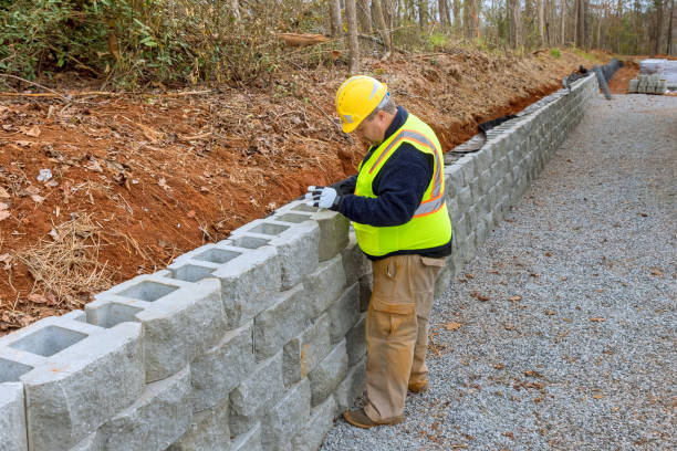 istock Construction worker, am mounting a retaining wall with concrete blocks to ensure its proper placement. 1592308372