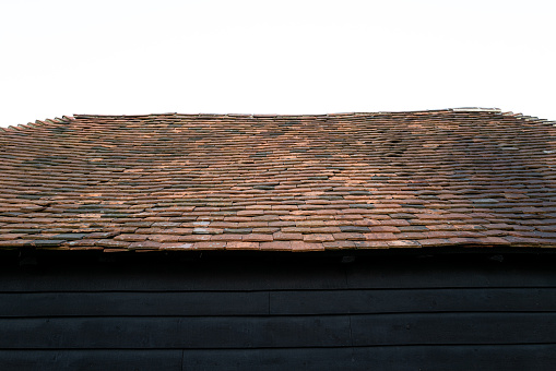 Abstract view of a old wooden black barn showing its very old tiled roof. The roof has recently had roof tiles replaced.