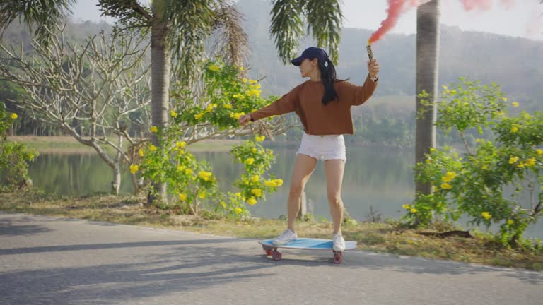 Asian women surf skate or skates board outdoors .
