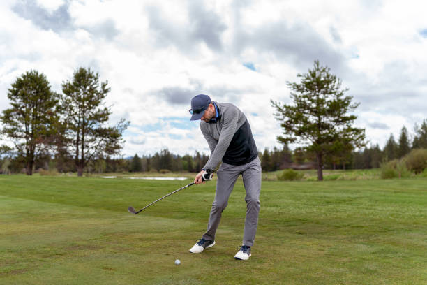 istock Male golfer ready to make contact with golfball while teeing off 1592337520
