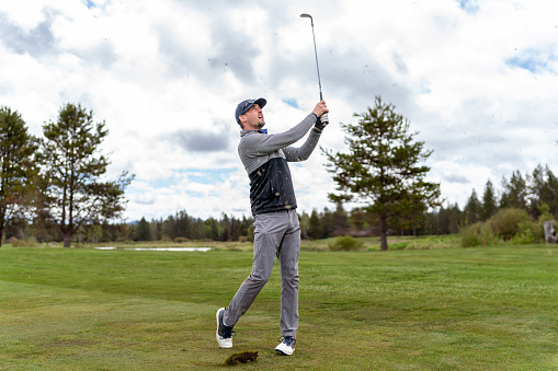 A golfer preparing to strike a golf ball on the golf course on a sunny day - Stock Photo