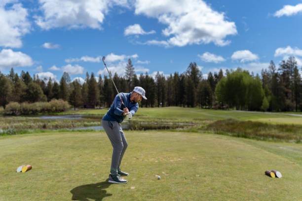 istock Young man swings golf club on the course 1592337527