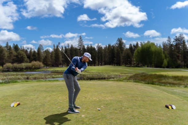 istock Young man swings golf club on the course 1592337528