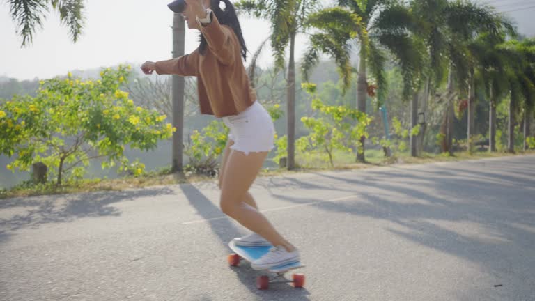 Asian women surf skate or skates board outdoors .