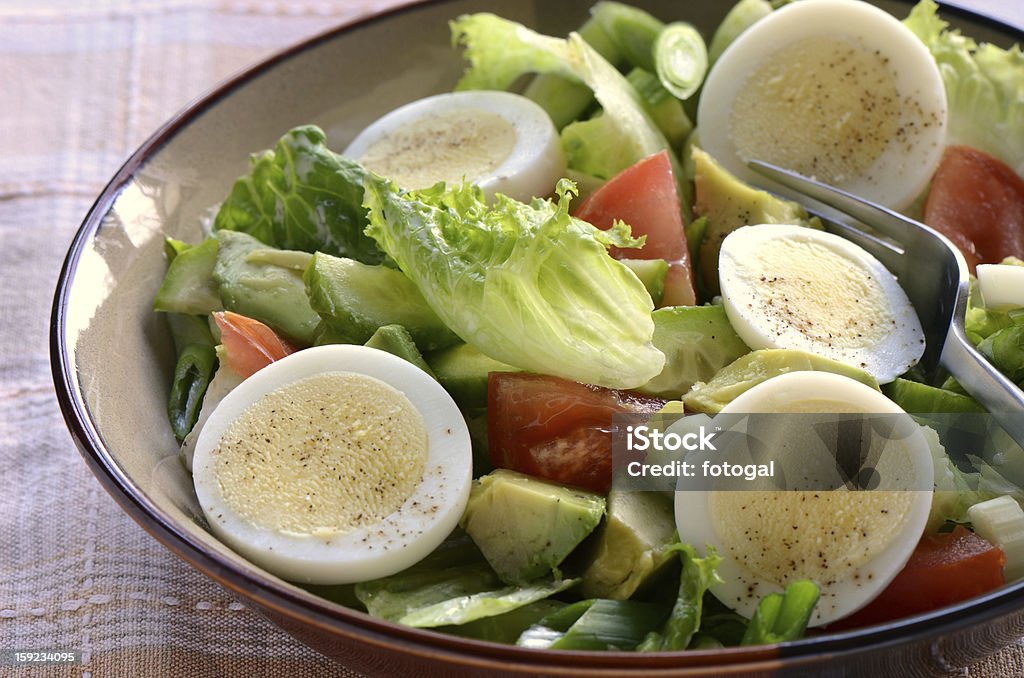 Garden salad with hard boiled egg Fresh garden salad with egg, avocado and tomato in brownstone dish for a healthy low calorie lunch. Avocado Stock Photo