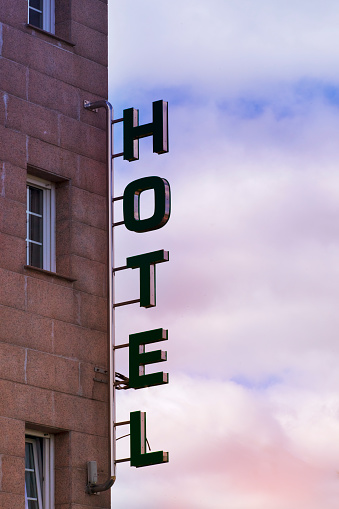 Close-up view of hotel sign on tall building facade at dusk, sunset background. A Coruña, Galicia, Spain.