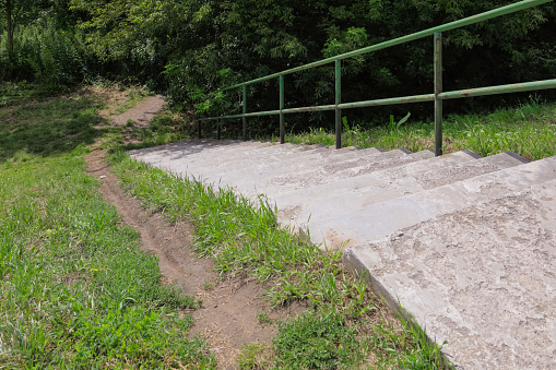On the slope of the massive levee there are concrete stairs with a metal railing, a path has been trodden next to the stairs. This dike separates the Vistula River from the Goclaw estate in Warsaw