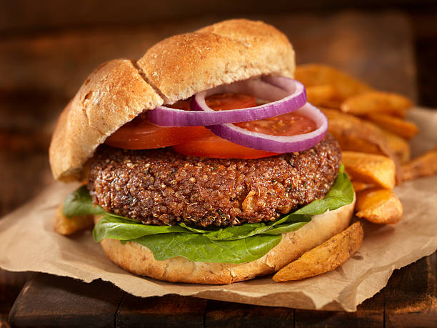 The Quinoa Burger A fantastic vegetarian burger made with quinoa, chick peas, rolled oats, crushed onions and garlic, spices on a Whole Wheat Bun with spinach, tomatoes and onion and a side of Oven Baked French Fries -Photographed on Hasselblad H3D2-39mb Camera veggie burger stock pictures, royalty-free photos & images