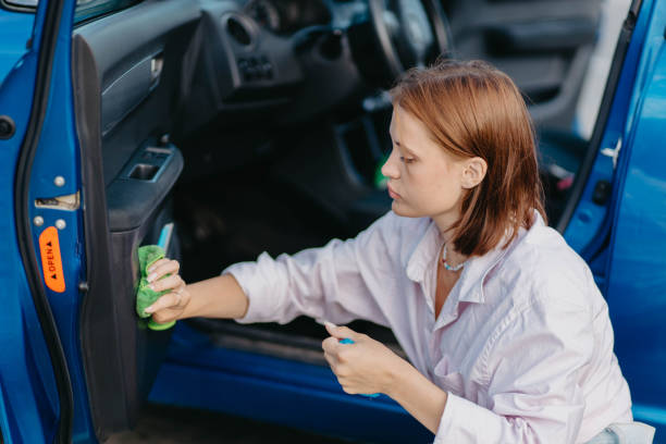 istock woman cleaning plastic car interior with microfiber cleaning agent Car interior detailing. 1592504440