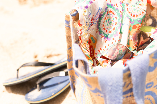 beach bag with sunglasses, dress and sandals on the sand in the summer.summertime concept
