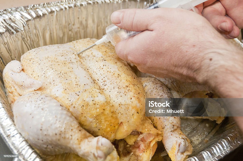 Macho Inyectar condimento en una materia prima de pollo - Foto de stock de Chef libre de derechos