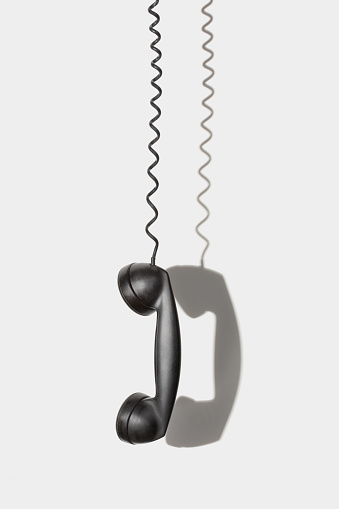 Hanging handset of an old phone against a wall