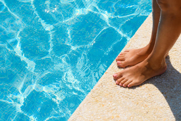 istock Women's feet by the pool on a summer day. Active recreation concept 1592618295
