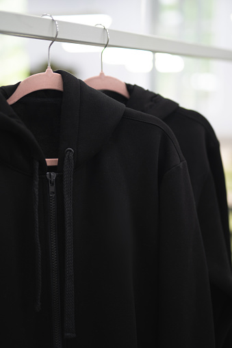 black hoodie clothes hang on hangers at the factory